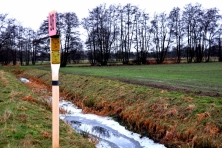 Gashinweisschild auf Feld an Graben